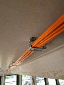 A cable bundle that goes through a series of metal brackets fixed on the ceiling